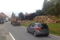 Holzstapel, Holzlaster und Autos entlang einer Straße
