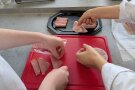Nahaufnahme von Händen, die Wurst auf einer Platte anrichten.