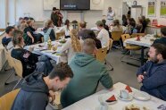 Personen sitzen im Klassenraum an Gruppentischen