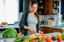 Schwangere Frau schneidet Obst und Gemüse. 