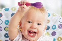 Lachendes Kleinkind hält Löffel über Kopf © iStock