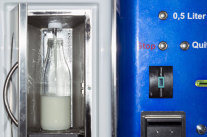 Milch fließt in Flasche am Milchautomat.
